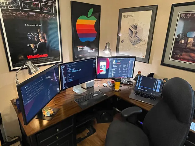 Scott's workspace: three monitors with code, a framed Apple rainbow-logo poster, and a Star Wars print